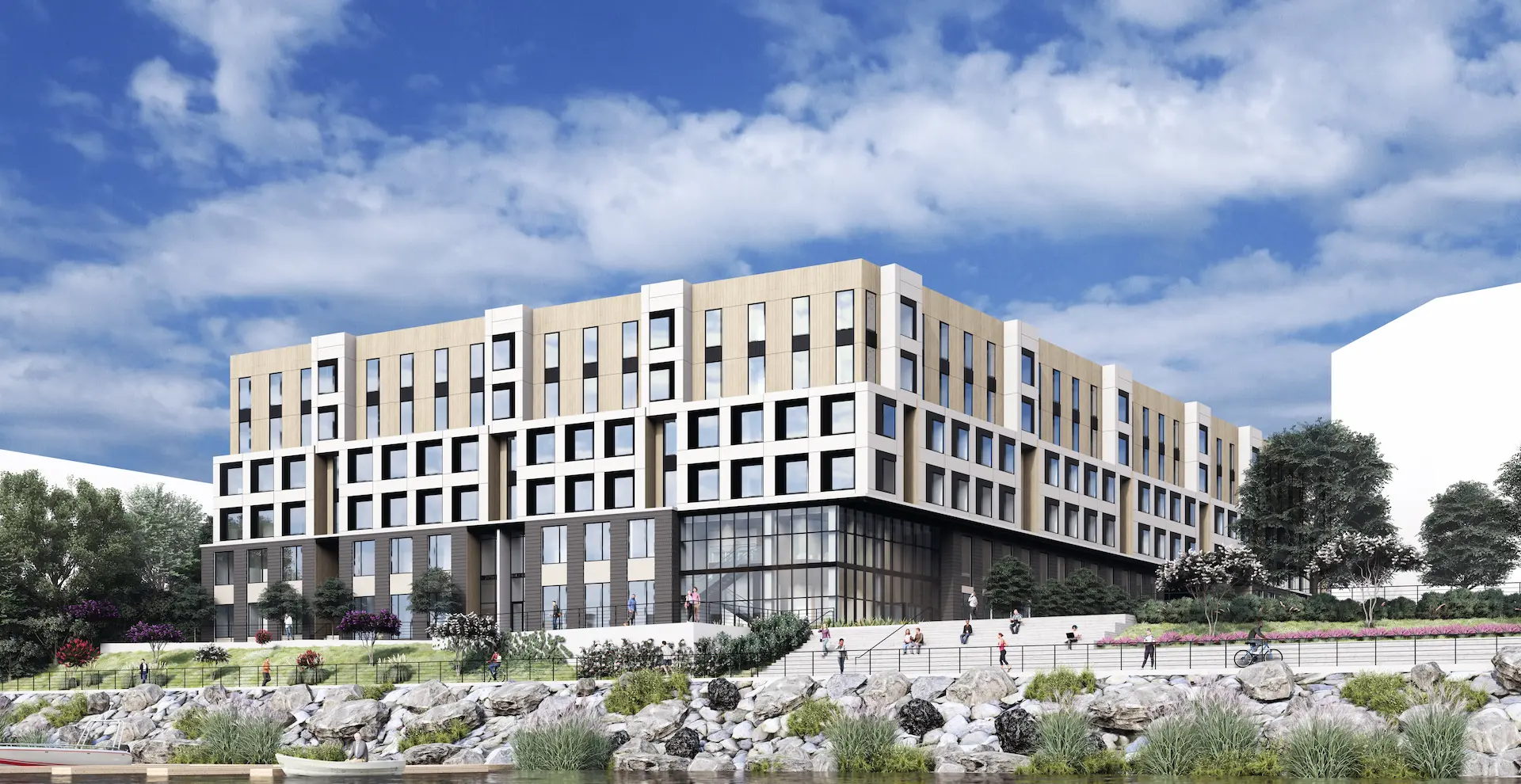 Student apartment building exterior with a mix of glass, dark brick, and white and tan stone against a blue sky with light clouds.